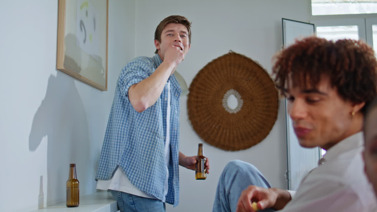 Young man hanging out with buddies holding beer bottle weekend gathering closeup