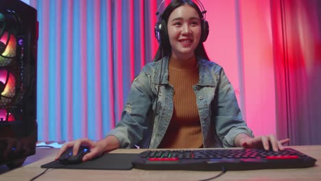 excited asian girl gamer playing video game on computer