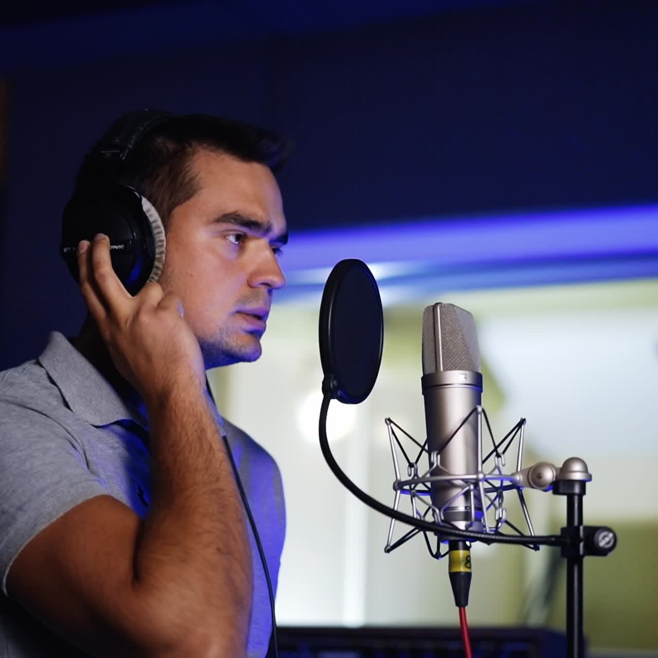 Male Caucasian singer performing song in the modern studio. Man sings a lyrical composition and then starts laughing