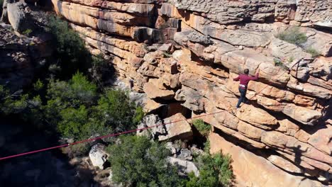 male highliner walkng on a rope over rocky mountains 4k