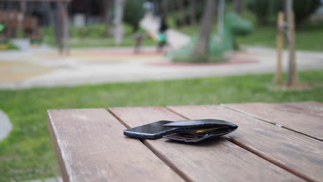 teléfono perdido y billetera en una mesa de picnic en un parque