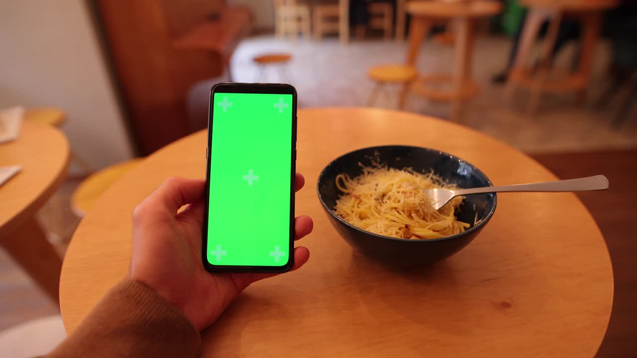 카페에서 스마트 폰의 빈 초록색 화면을 들고 있는 남자 손