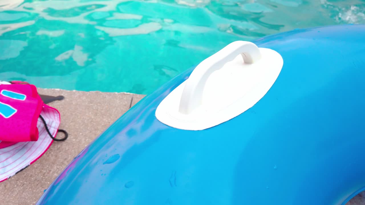 Blue inflatable boat next to a swimming pool during the day, outdoor, pan shot
