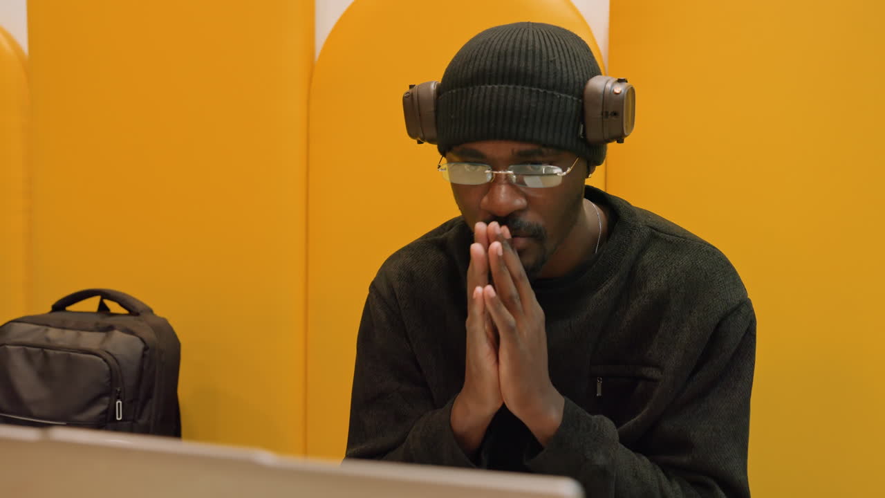 Man concentrating during urgent review. Person under stress in vibrant booth during critical conference. Dedicated professional intensely reviewing code amidst deadline pressures in lively workspace