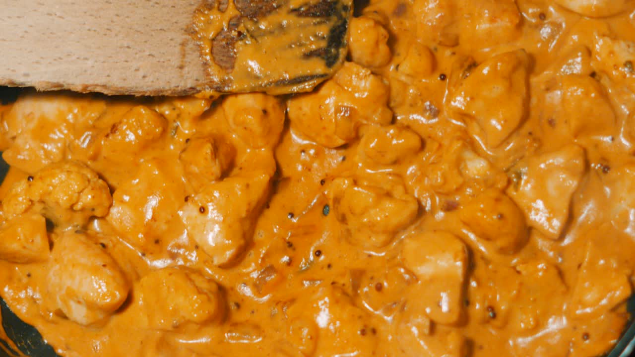 Top View of Chicken Keralan Curry Cooking in Pan with Wooden Spatula Resting on Top. Tasty Spicy South Indian Dish