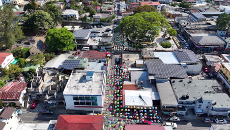 Toma-Aérea-De-Pájaro-De-Un-Colorido-Paraguas-Decorado-Sobre-La-Calle-En-Jarabacoa,-República-Dominicana