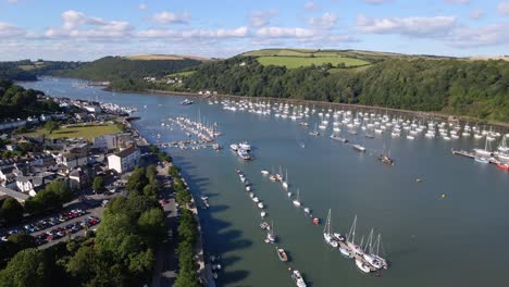 aerial over dart river in kingswear, devon w uk, many sailing boats on the river in the middle of the green shore