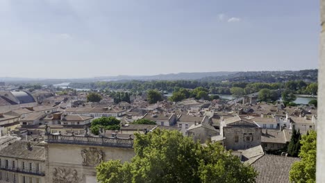 panning over french town with many old stone houses and historic buildings and churches in good weather and balmy sky and green hills on the horizon