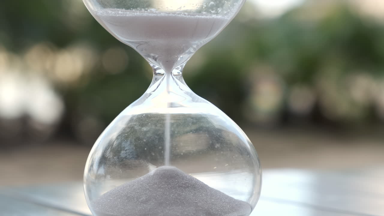 Hourglass as time passing on wooden table with bokeh background