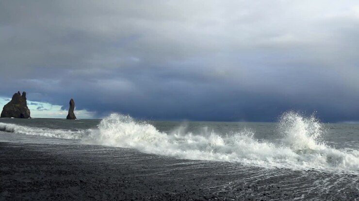 Les vagues s'écrasent sur la plage de sable noir