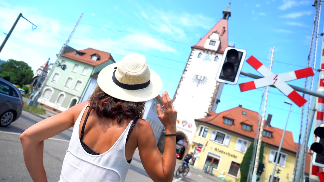 Frau mit Hut in einer Stadt mit einem Turm und einem Bahnübergang