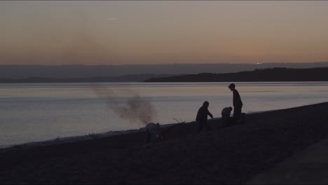 una vista de la gente haciendo fuego en la playa del mar durante la puesta de sol