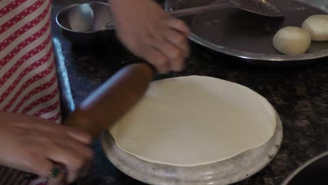 rolling chapati with roller in kitchen