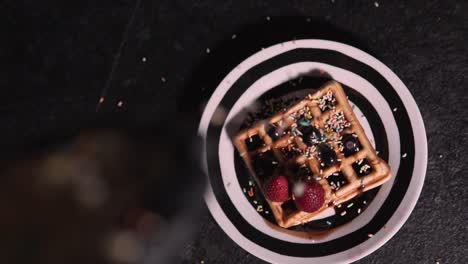 confetti slowly falling into waffle healthy and fitness waffle decorated with red berries, chocolate syrup and colored confetti. healthy cooking and fitness