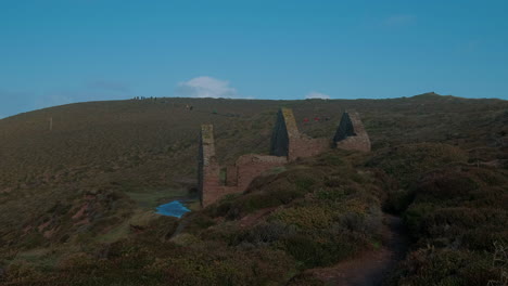 Gebäude-Der-Zinnmine-In-Cornwall-An-Der-Nordküste-Cornwalls-Mit-Menschen,-Die-Den-Küstenpfad-Entlang-Wandern