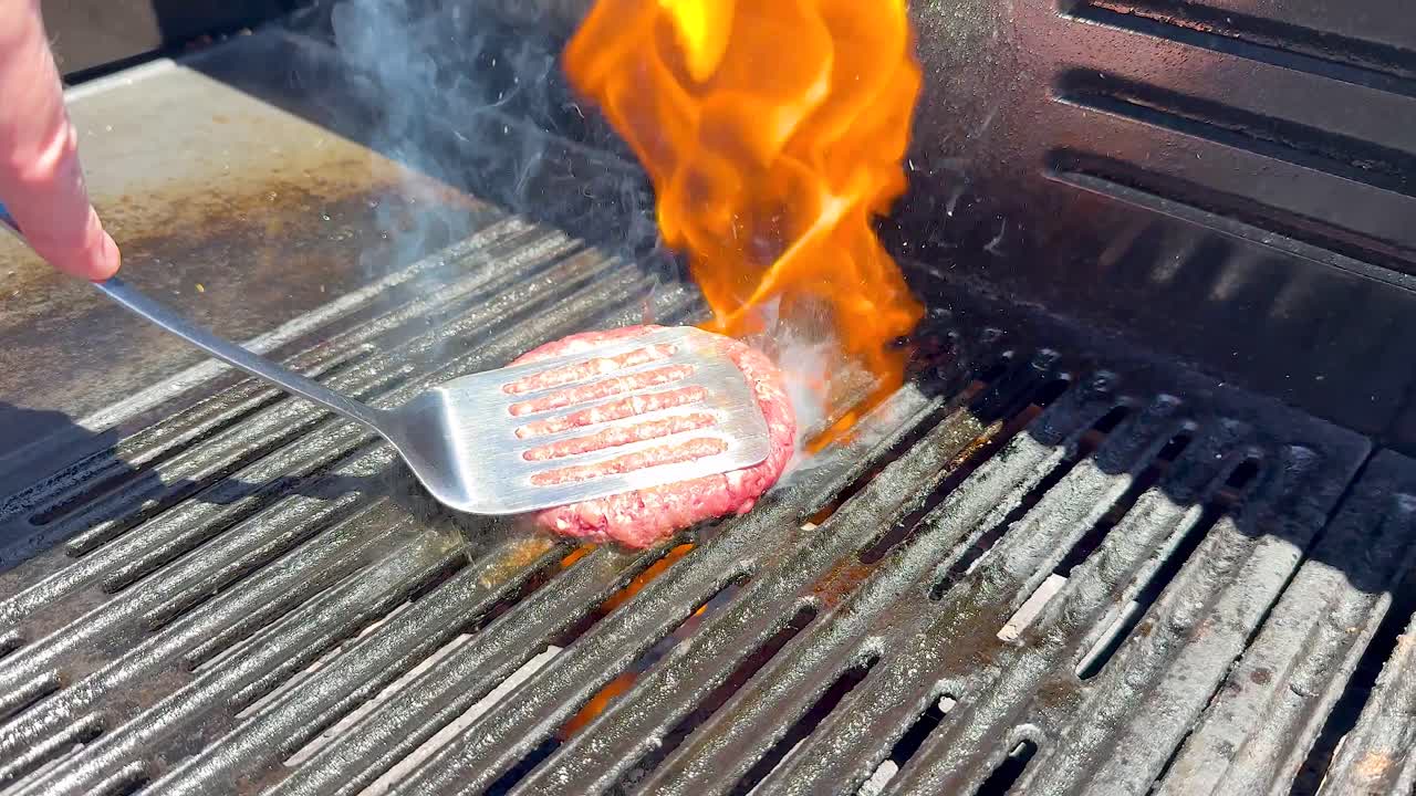 불타는 그릴에서 햄버거 패티를 조리하고 있다