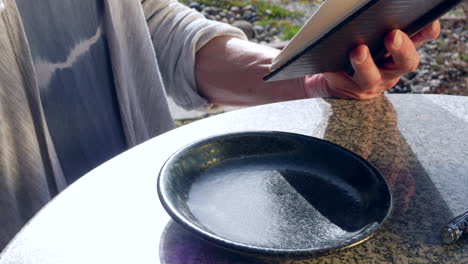 close up on an elderly woman reading a book and drinking a cup of herbal tea in the morning sun