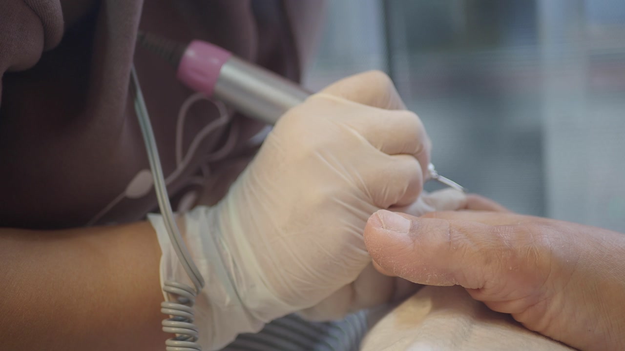 Nail Technician Performing Pedicure with Electric File
