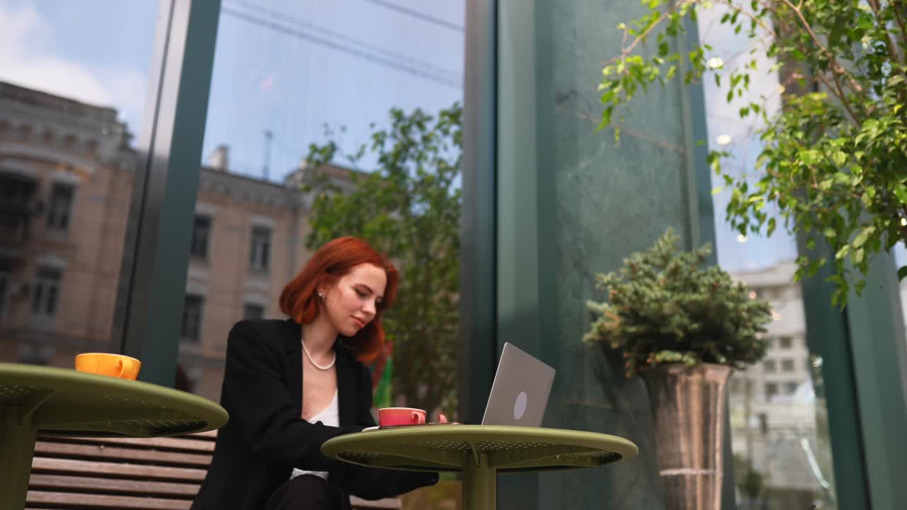 Donna che lavora al portatile in un caffè all'aperto