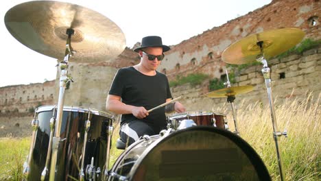 musician drummer, playing drum set and cymbals, on street in sunny weather