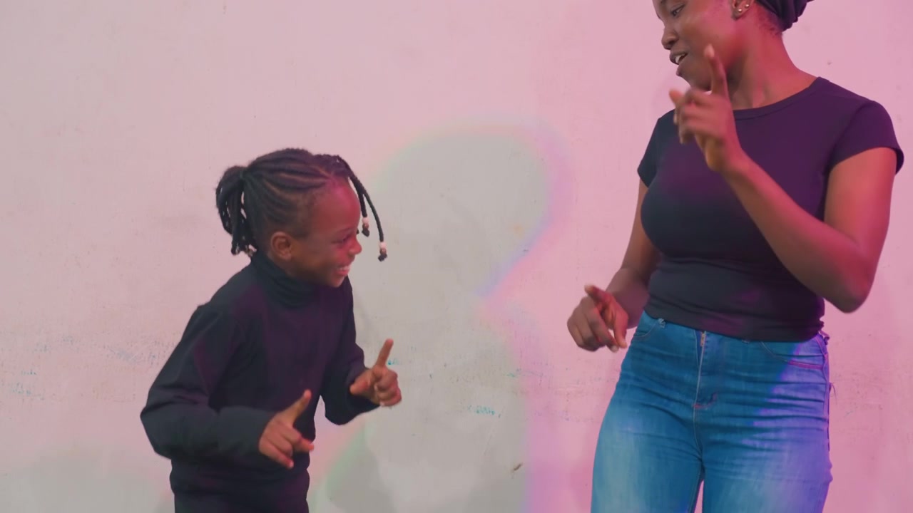 Famiglia che balla gioiosamente. Madre e figlia si godono una danza vivace. Madre e figlia giocose ballano con felicità. Una madre e una figlia energiche condividono un ballo divertente sotto un'illuminazione rosa, con sorrisi.