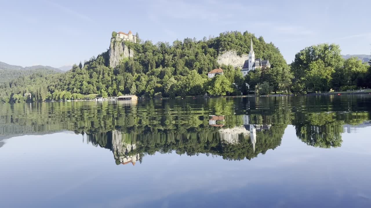 Bellissimi riflessi sul Lago di Bled con vista sulla Chiesa e sul Castello di Bled in una limpida mattina estiva di sole