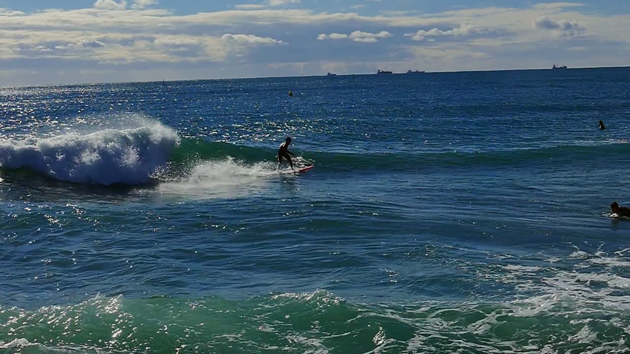 Slow motion (120fps): male surfer surfing the wave and crashing in Barcelona, Spain