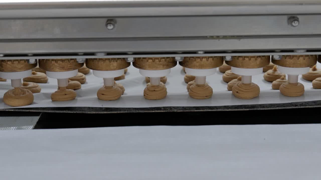 Industrial pastry machine depositing dough portions on baking paper in a French bakery production line