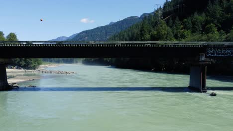 Breathtaking-drone-dolly-shot-under-a-bridge-over-a-turquoise-river