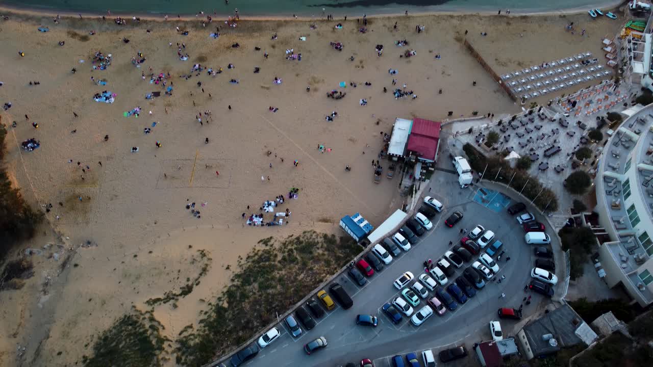 몰타의 해변  ⁇ 에 있는 활기찬 마을의 장면을 드러내는 오버헤드  ⁇ 은 드론 카메라에 의해 포착되어 거리에서 이동하는 자동차와 오래된 건물이 캐릭터를 추가하는 것을 보여줍니다.