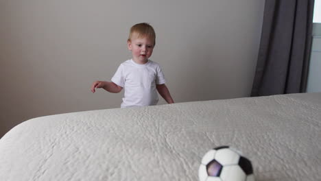 the boy is standing in front of the parents' bed and having fun with their parents