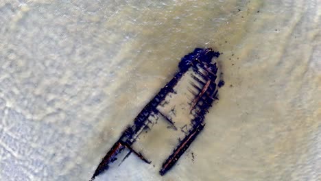 un naufragio en una playa, con agua turquesa que lo rodea, tomado con un dron