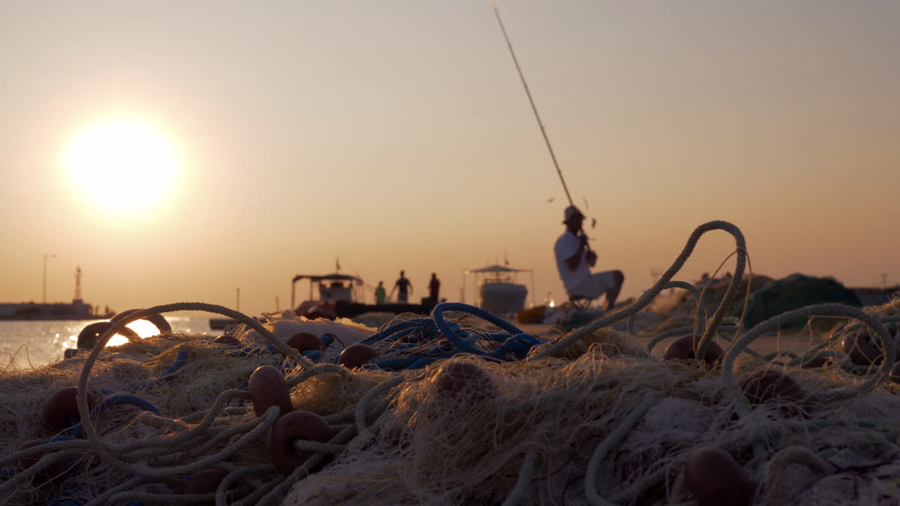 Hombre pescando desde el muelle en el puerto al atardecer