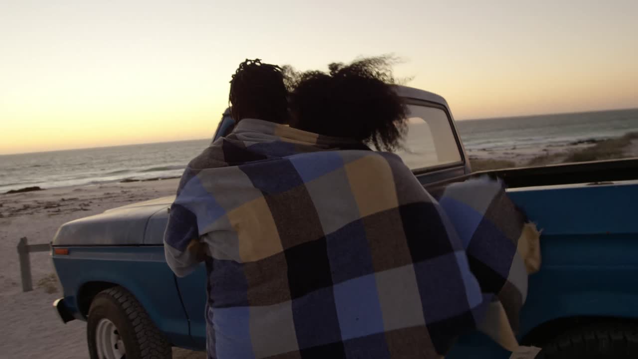 pareja envuelta en una manta y caminando juntos cerca de una camioneta 4k
