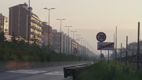 speed limit and end of milan city sign and suburb apartment buildings during sunrise