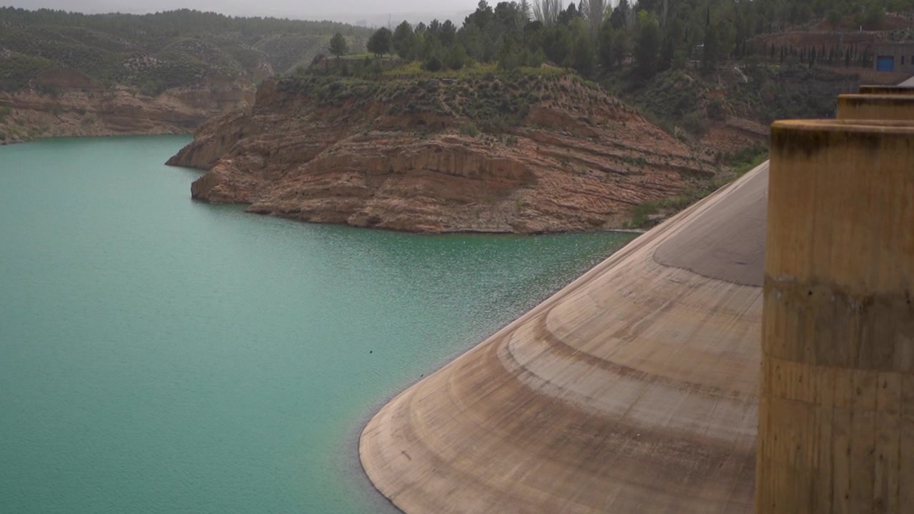 Pemandangan Dam Negratín yang tenang, air pirus, lanskap berbatu, Granada, Spanyol