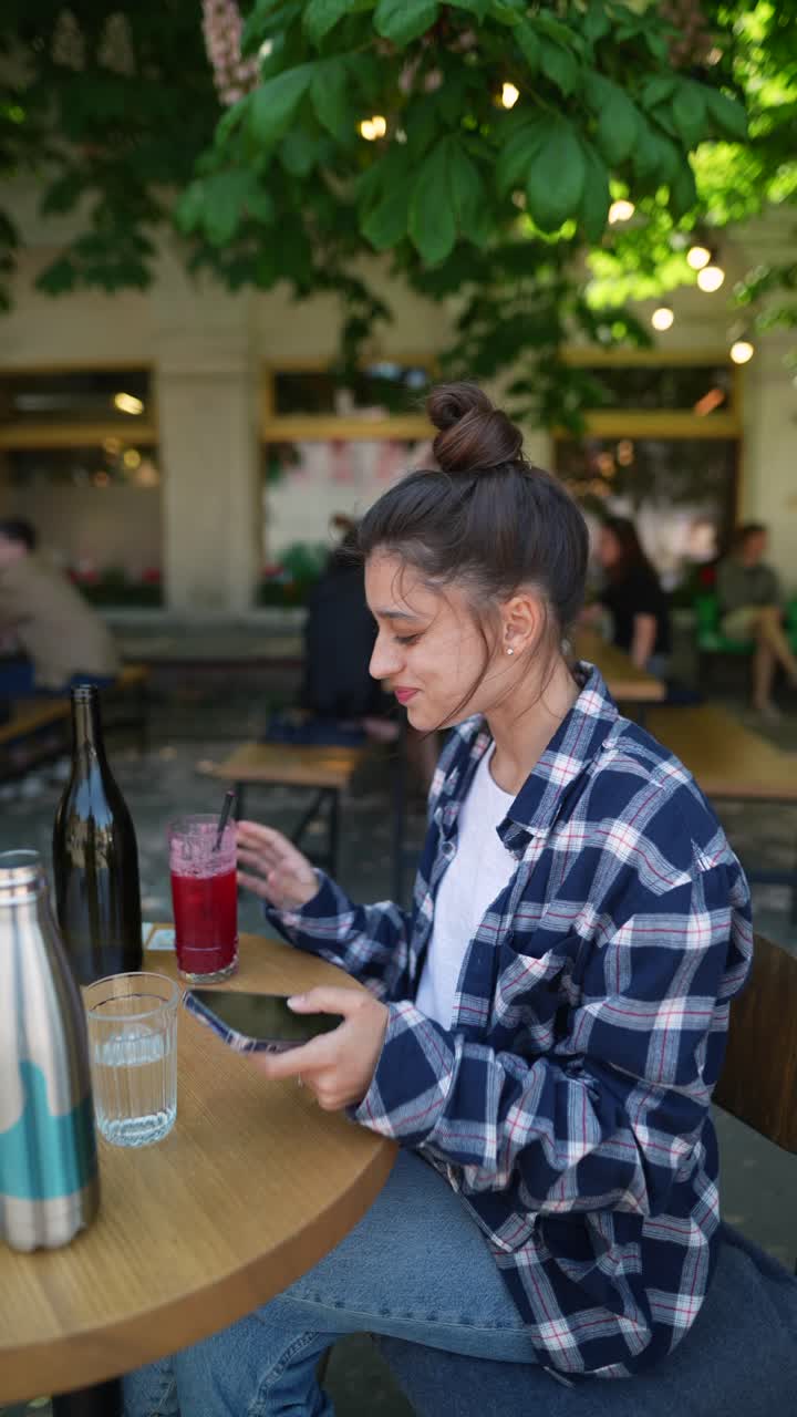 joven usando el teléfono en un café al aire libre