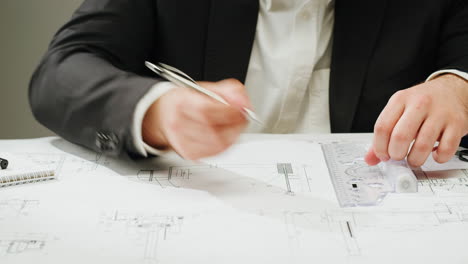 person drawing on blueprints with a ruler and pen