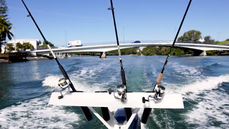 fishing rods on boat moving under bridge