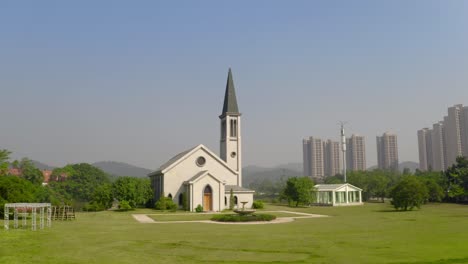 catholic style church building without a cross surrounded with green grass fields on a bright clear day