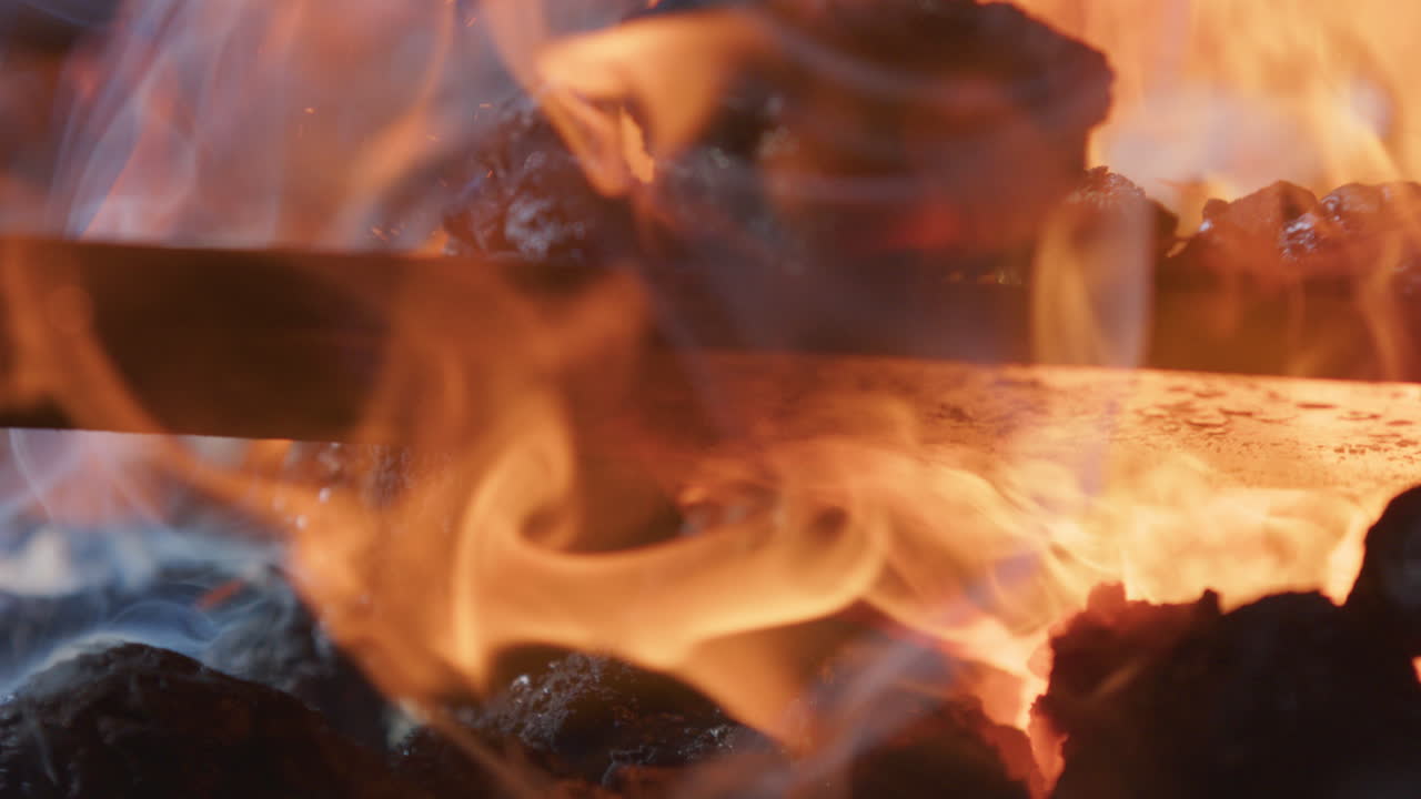Extreme closeup, metal piece heated in flames and coals of blacksmith's forge