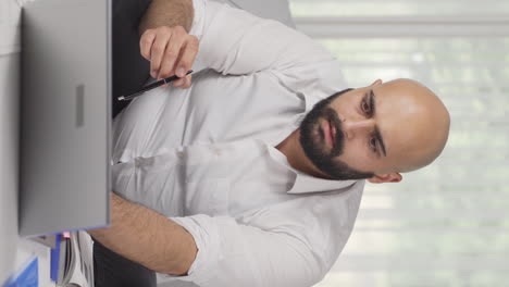 Vertical-video-of-Home-office-worker-man-has-trouble-focusing.