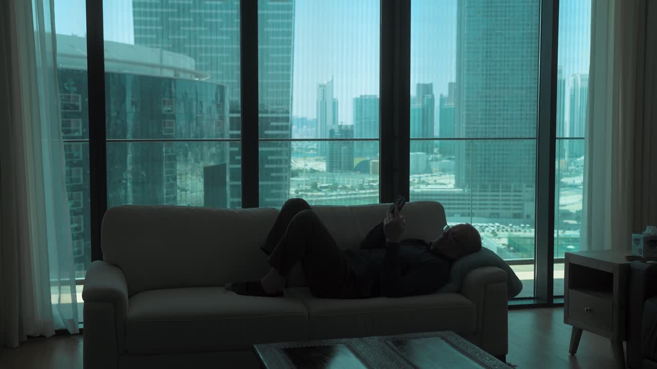 시내 아파트에서 스마트폰을 스크롤하는 중독자 인 소파에 누워있는 노인