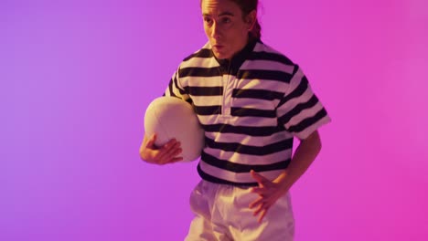 caucasian female rugby player running with rugby ball over neon pink lighting