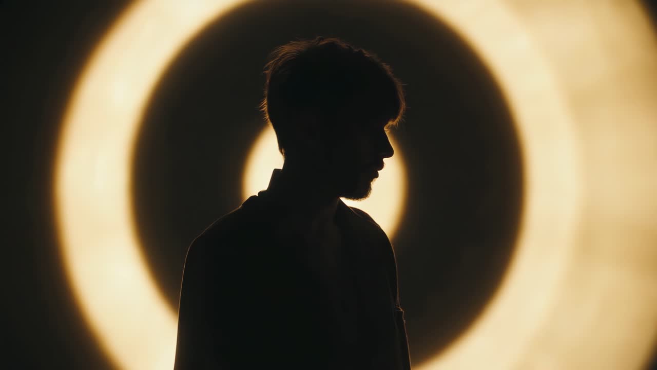Man's Silhouette Against Concentric Light Background