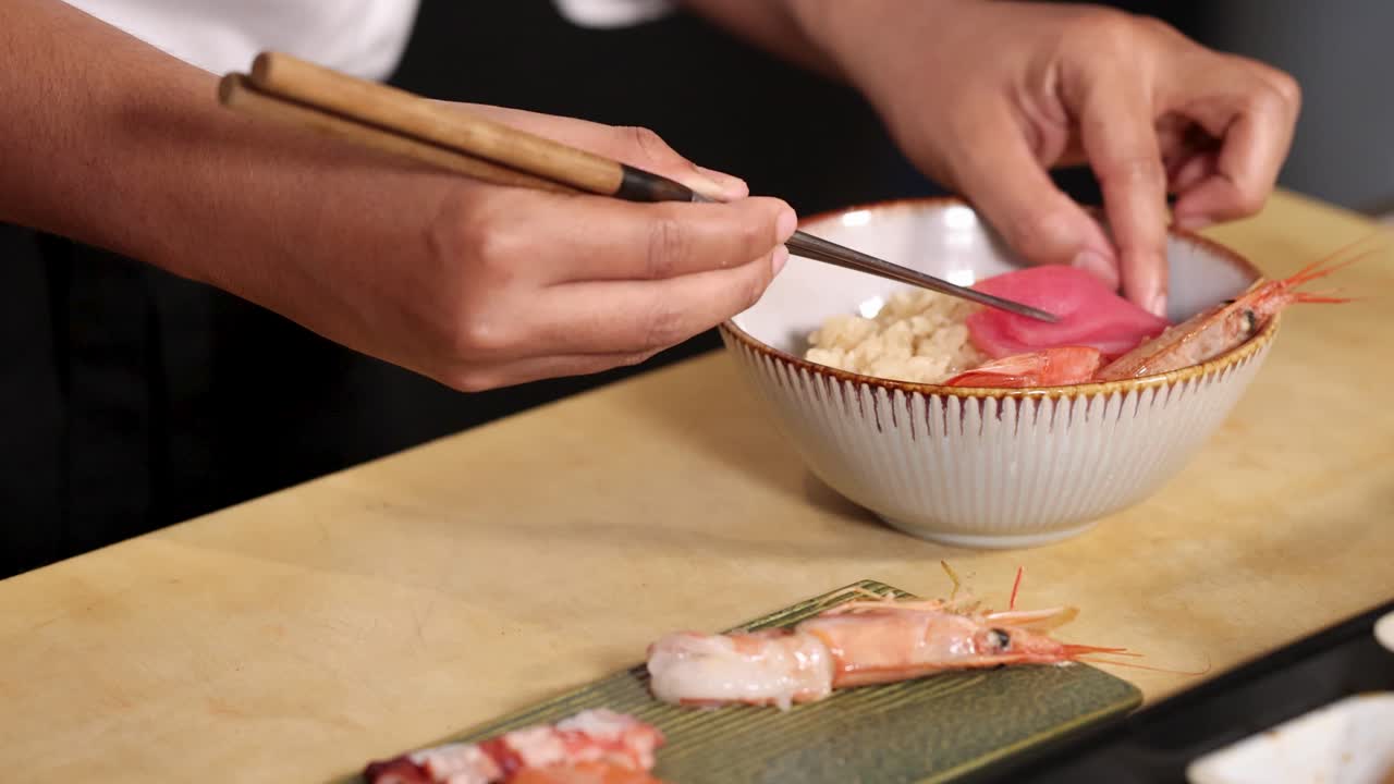 Primo piano di uno chef che impiattata sashimi di tonno e salmone su riso con una leggera illuminazione da studio