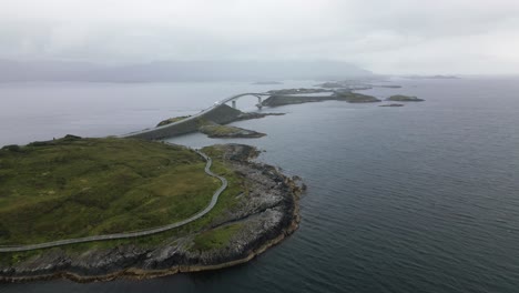 Gran-Carretera-Con-Un-Puente-Sobre-Muchas-Pequeñas-Islas-Rocosas,-Mar-Del-Norte-Y-Montañas,-Atlantikstreet,-Paisaje-Del-Archipiélago,-Noruega,-Naturaleza,-Drone