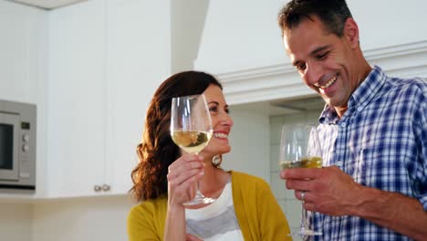 feliz pareja brindando vasos de vino en la cocina