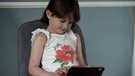 the girl sits back interacting with a tablet with full attention