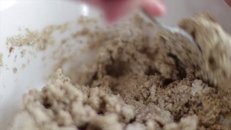 mixing dough mixture in bowl with a spoon - close up slowmo